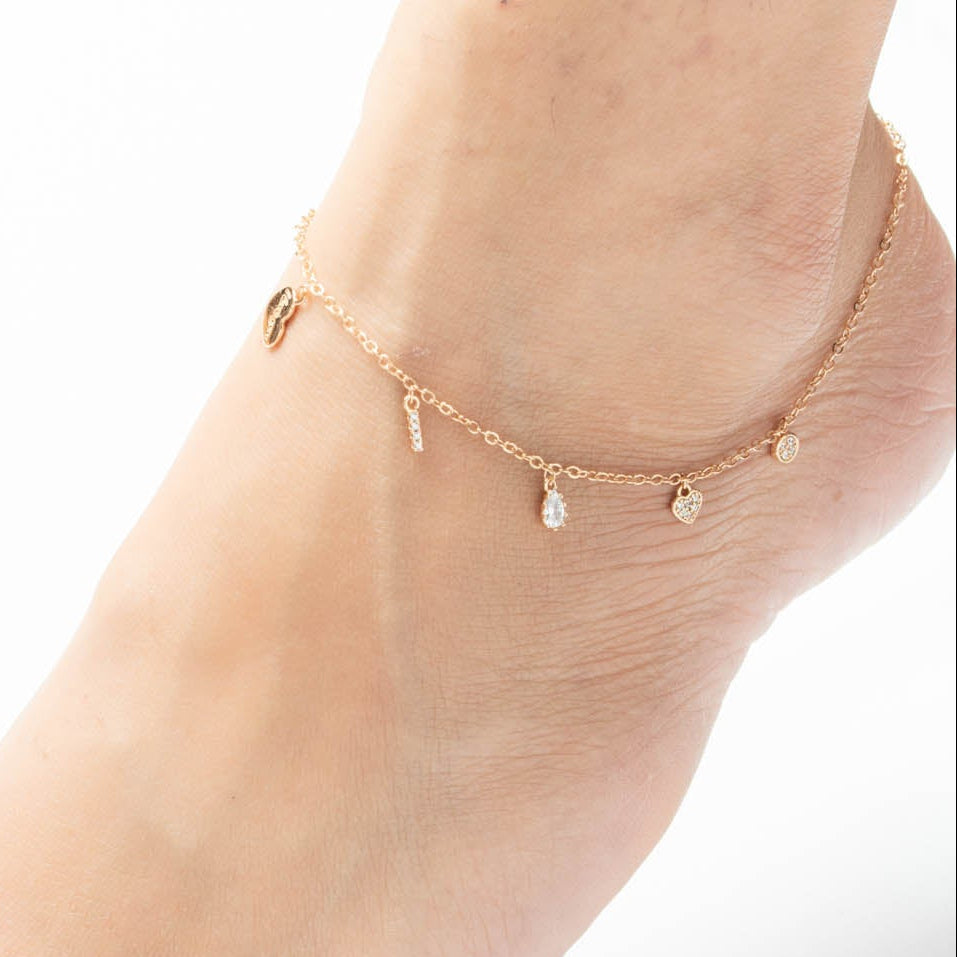 Gold anklet on a foot with a white background