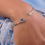 Multicolored heart-shaped bracelet on a wrist with denim background