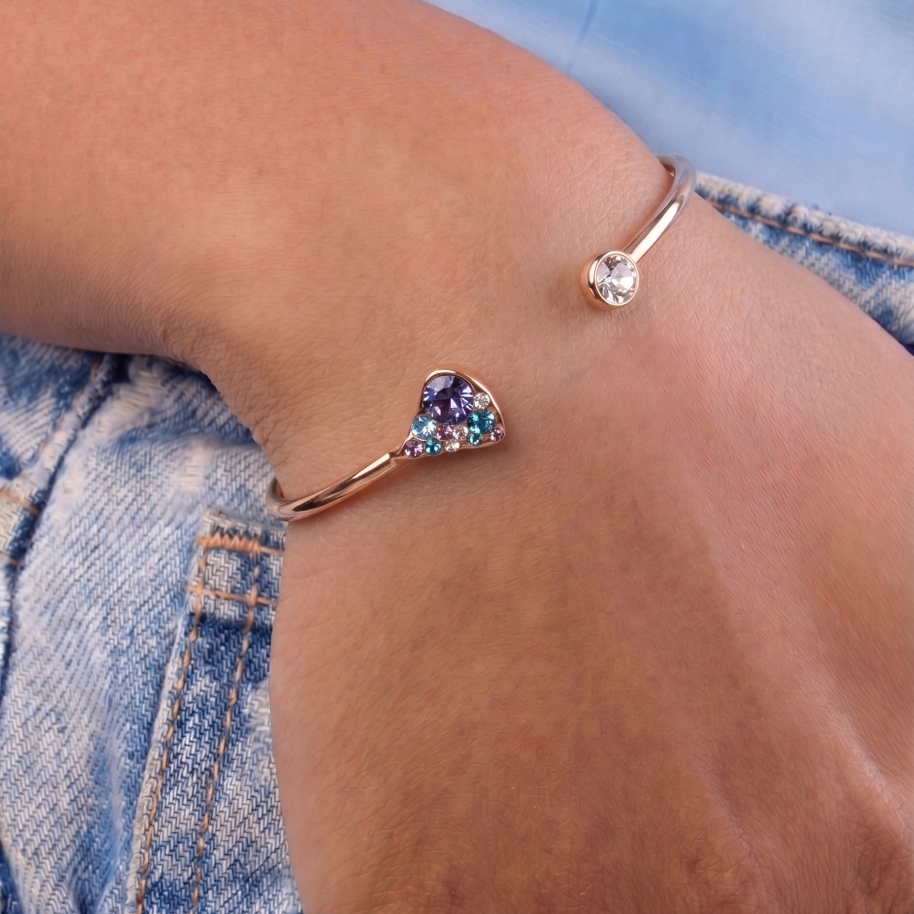 Multicolored heart-shaped bracelet on a wrist with denim background
