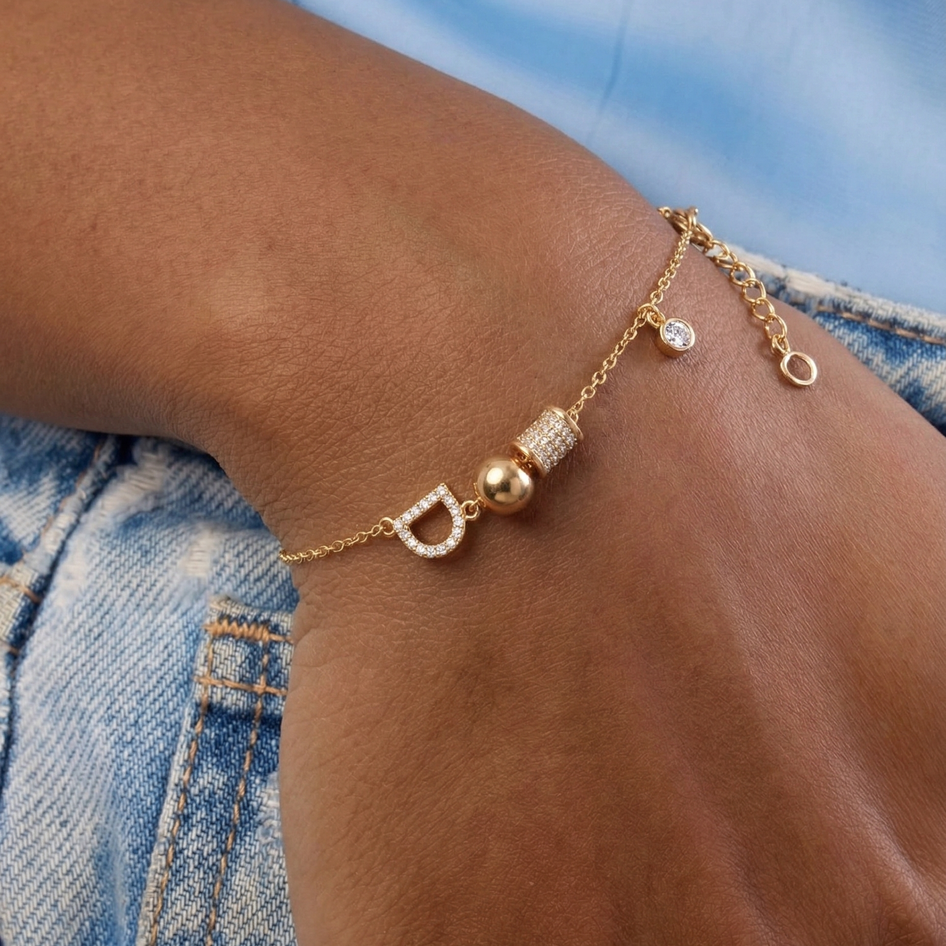 Gold anklet with decorative beads on a person's ankle against a denim background
