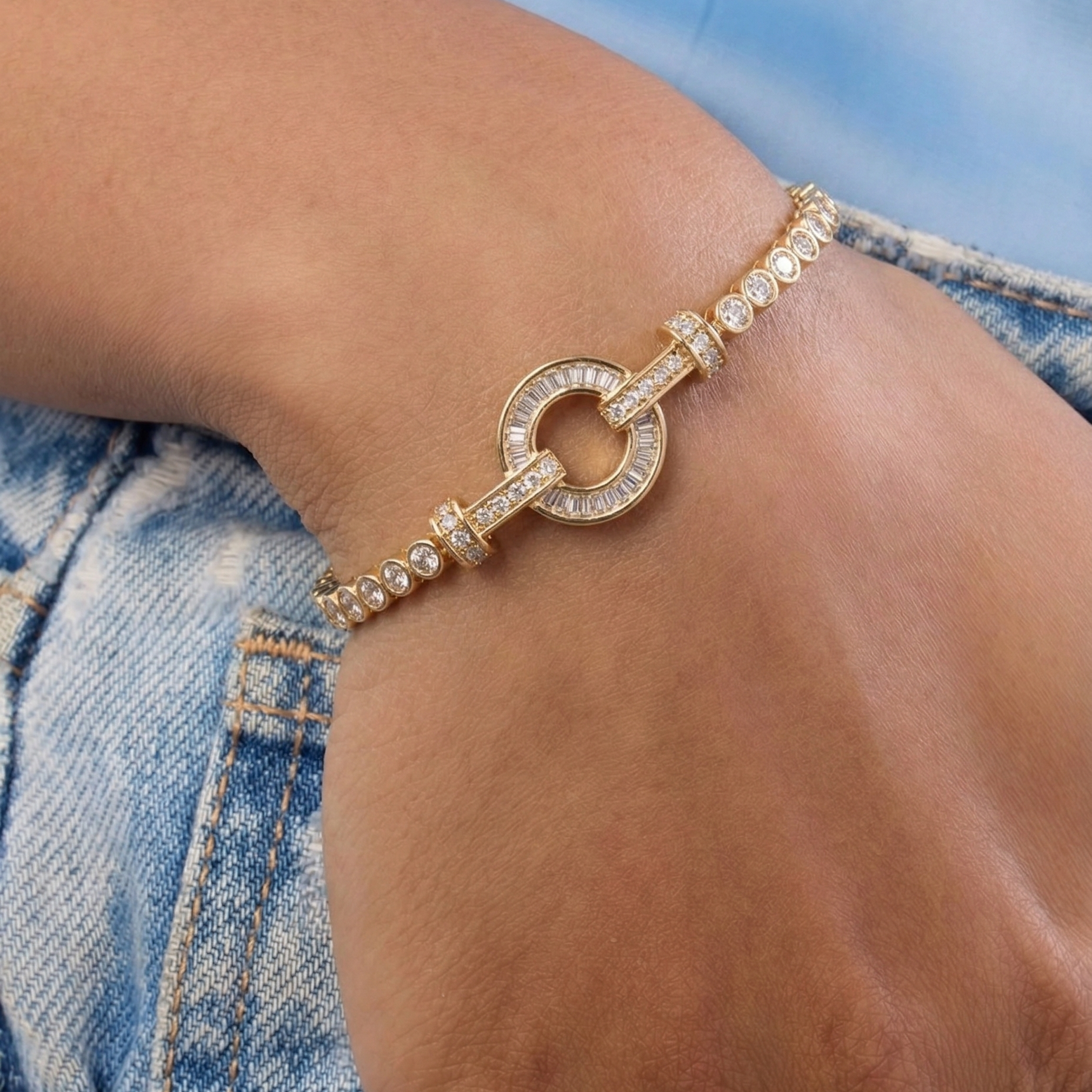 Gold bracelet with pearls on a wrist against a denim background
