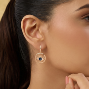 Close-up of a woman wearing an eye-shaped earring with a gold frame.