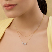 Close-up of a woman wearing a gold necklace with star-shaped pendants on a beige background