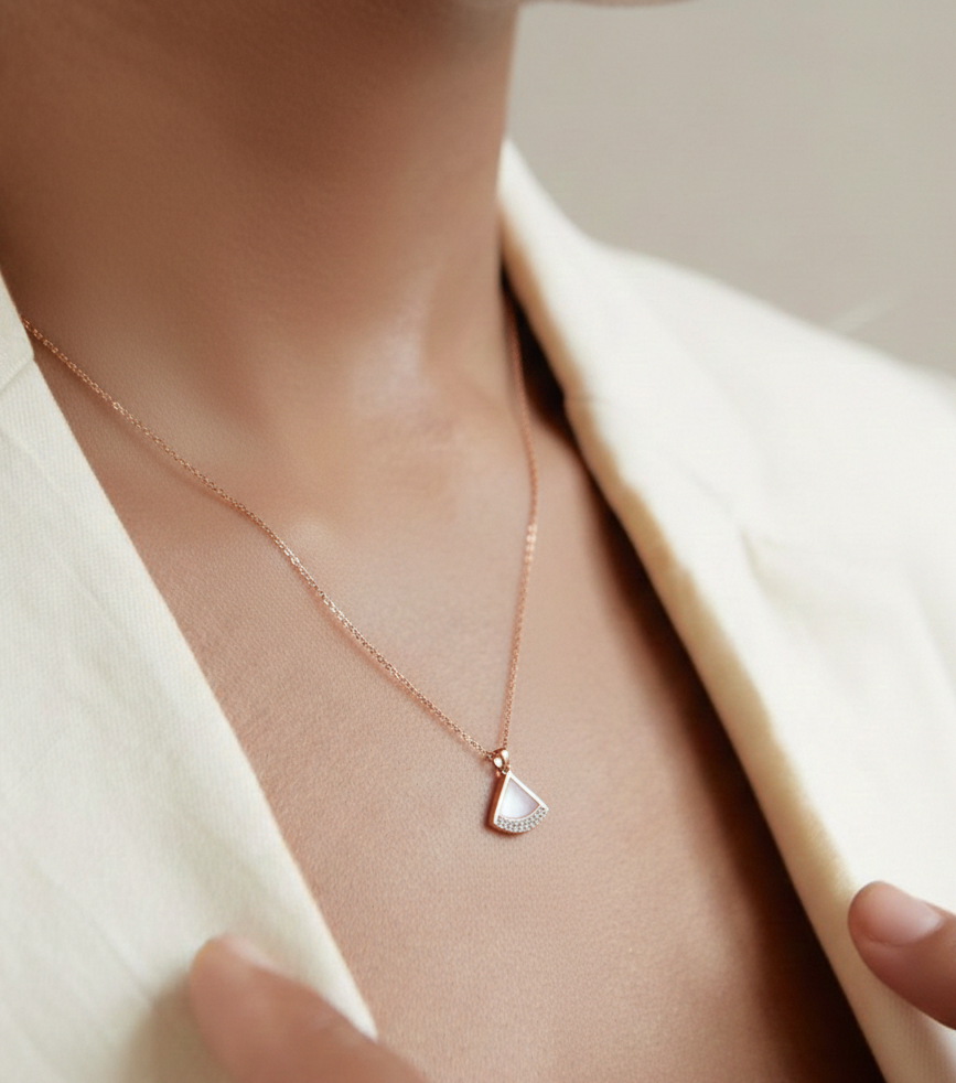 Necklace with a heart-shaped pendant worn by a person in a light-colored outfit.