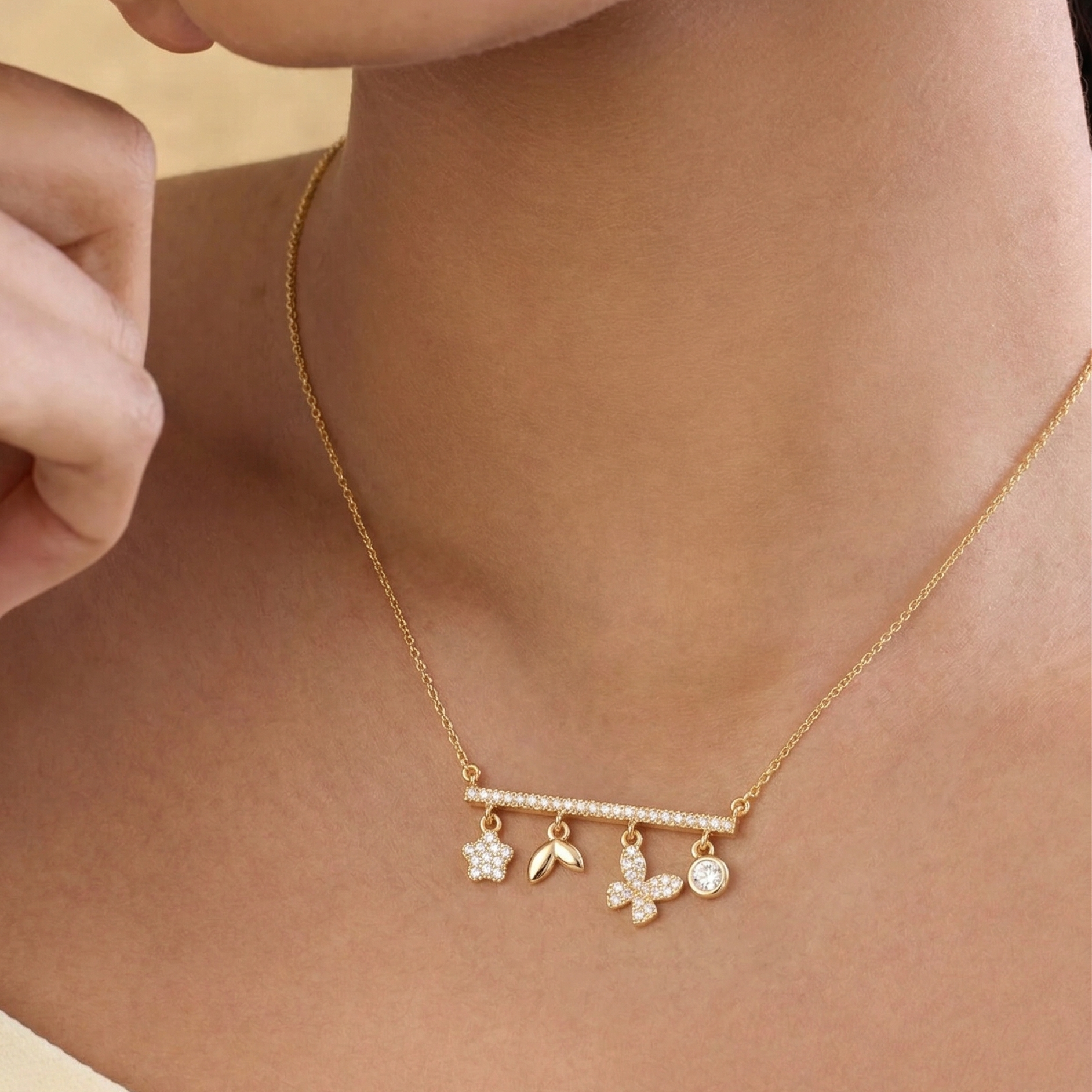 Gold necklace with butterfly and flower charms on a person's neck