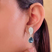 Close-up of an earring worn on an ear with a neutral background