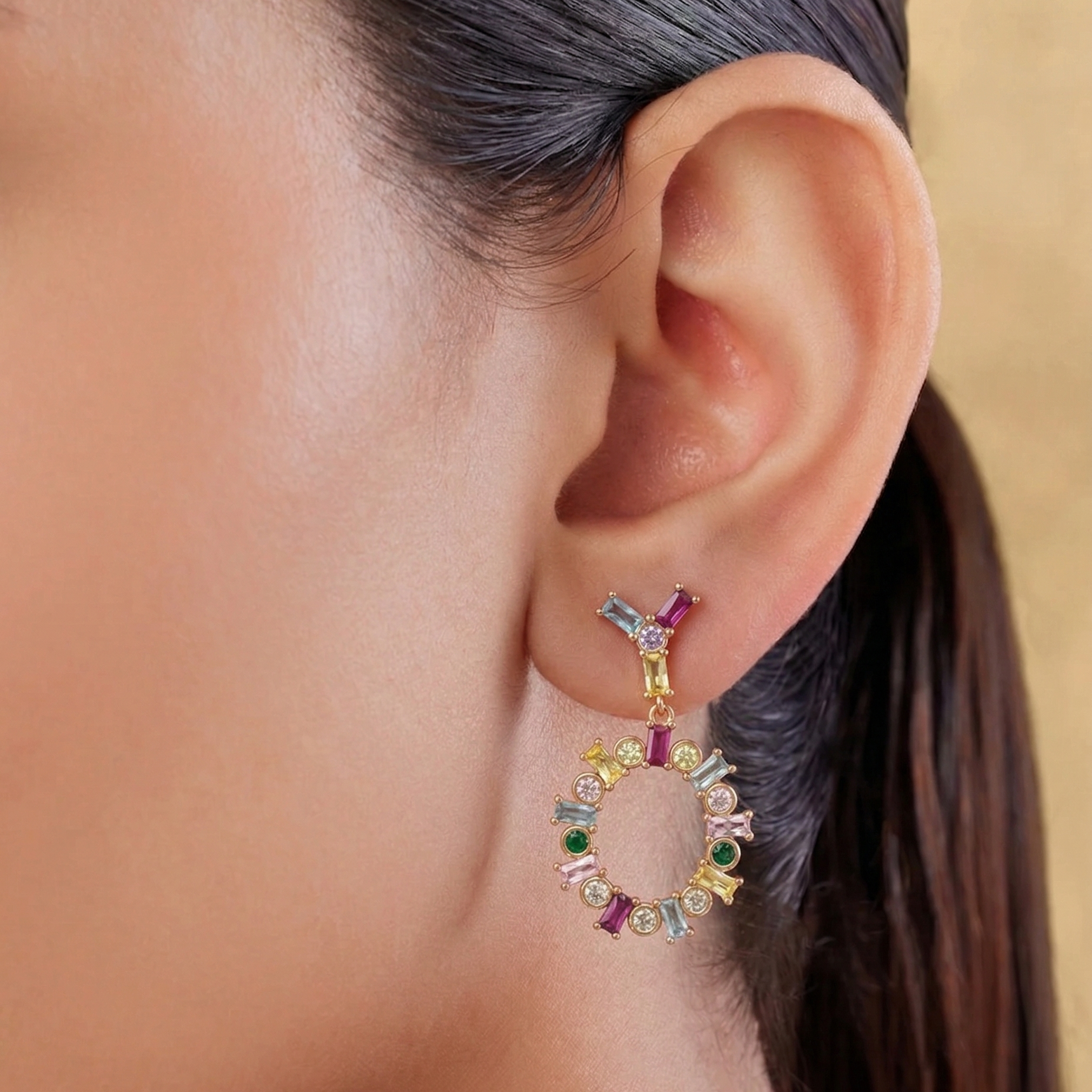 Close-up of an ear wearing a colorful earring with a neutral background