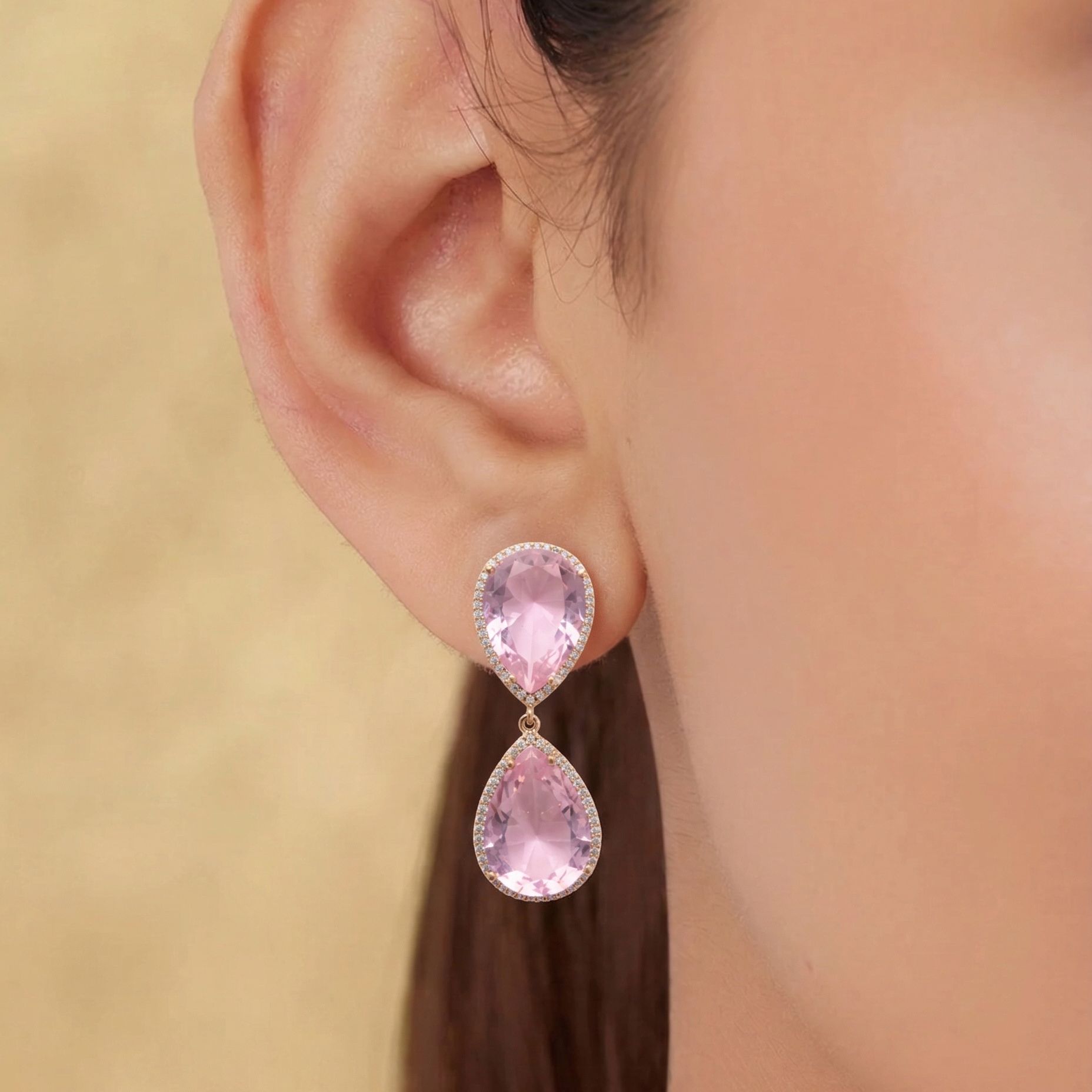 Pink teardrop earrings worn by a person with a neutral background