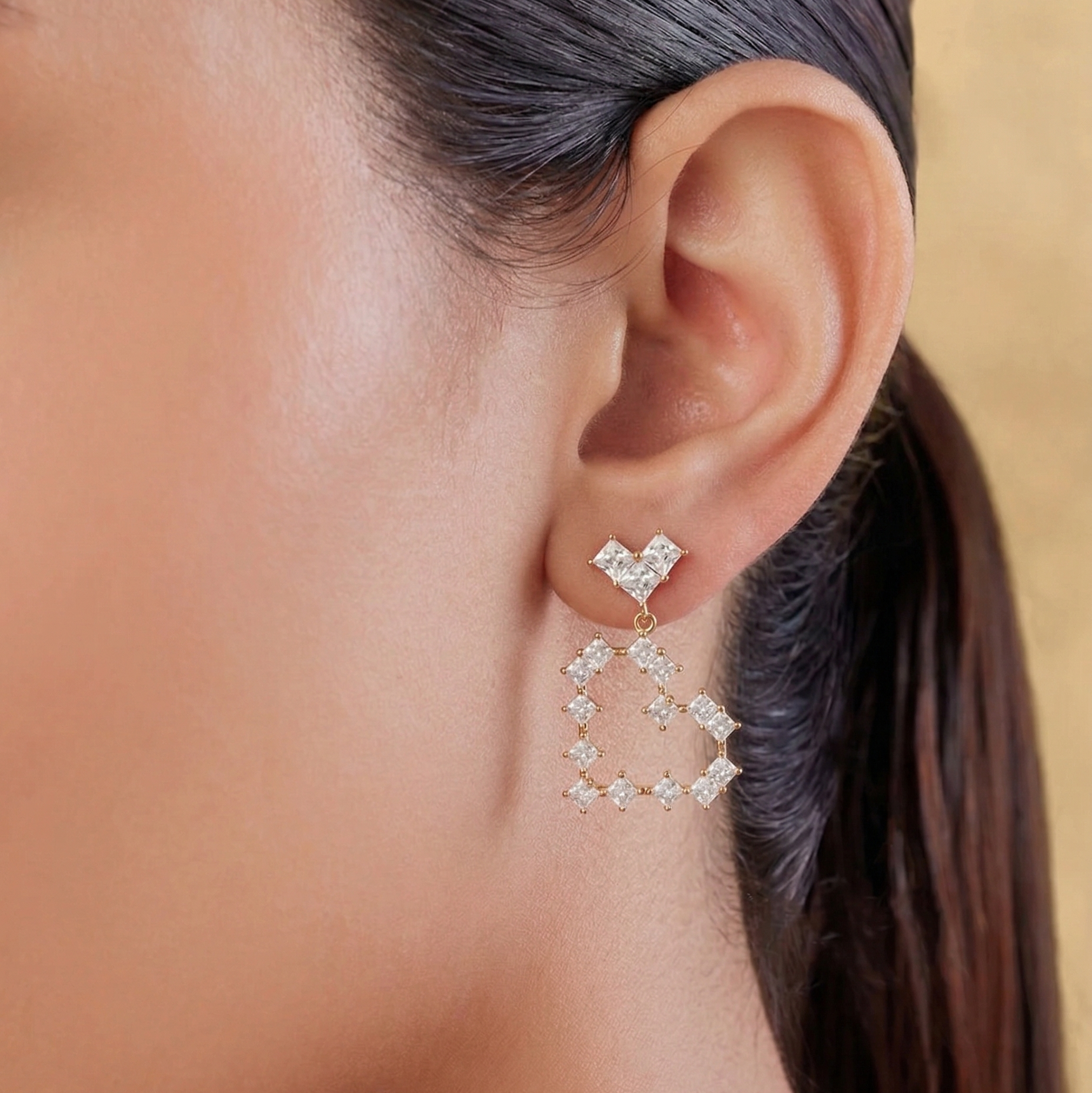 Close-up of a person wearing diamond earrings with a neutral background