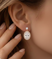 Close-up of a diamond earring worn by a person with a hand touching the ear.