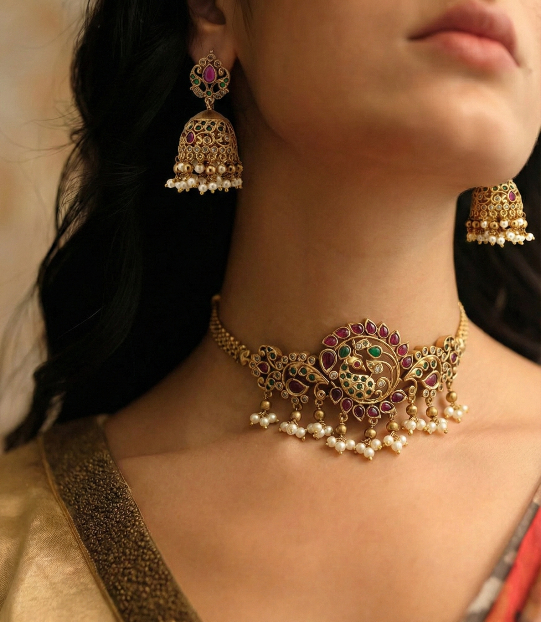 Close-up of a woman wearing an ornate gold necklace and earrings with a blurred background