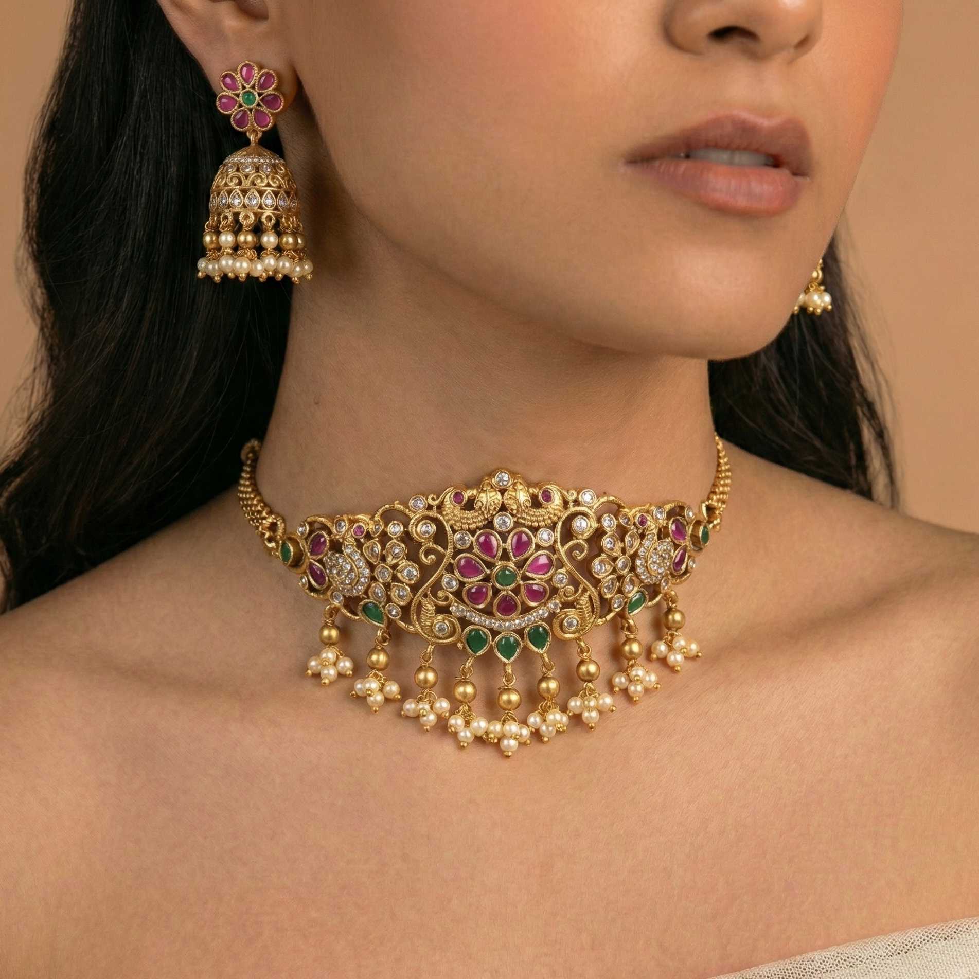 Gold necklace with pink and green accents worn by a model against a neutral background