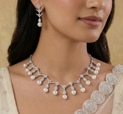 Woman wearing a pearl necklace and earrings with a beige background