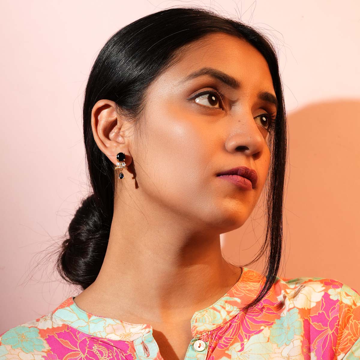A pair of Midnight Sapphire Drop Earrings with round sapphire studs and cascading blue teardrop shapes with sparkling crystal accents worn by a women. 
