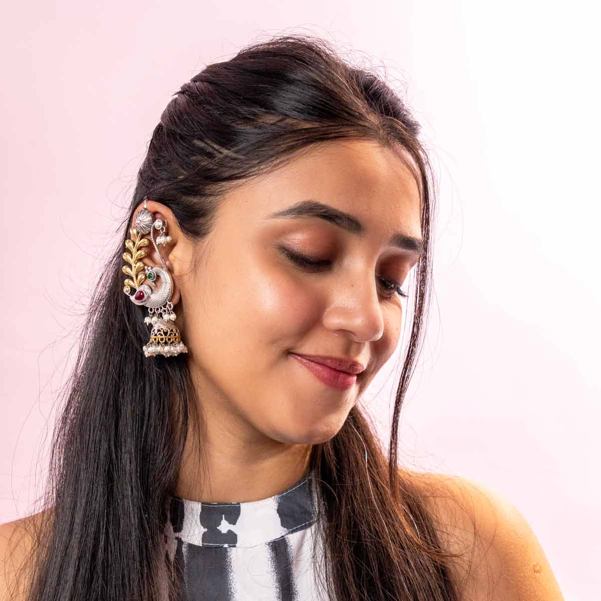 Woman wearing traditional earrings with a pink background