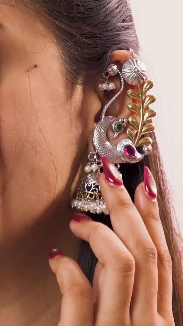 Load video: A woman flaunting peacock decorative earring on pink background.